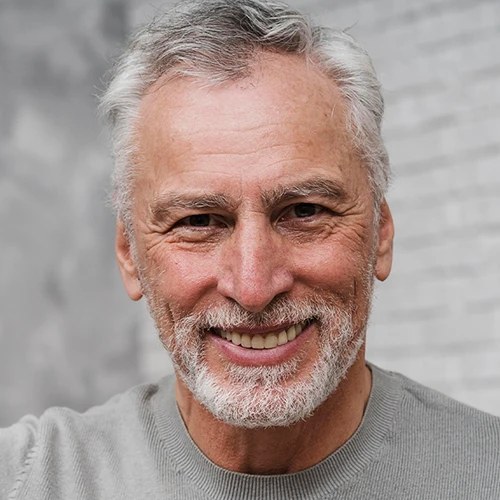 A smiling gray-haired man in a gray sweater
